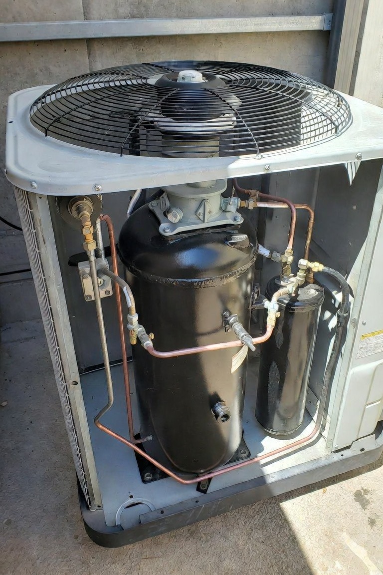 Internal view of an HVAC compressor inside an outdoor condenser unit